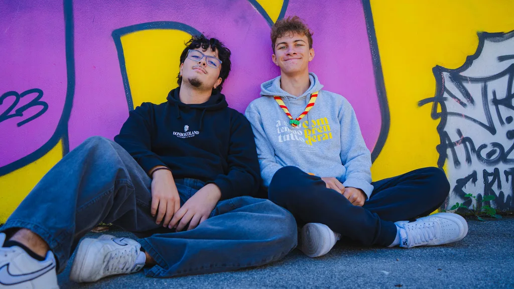 Due ragazzi seduti davanti a un murale colorato