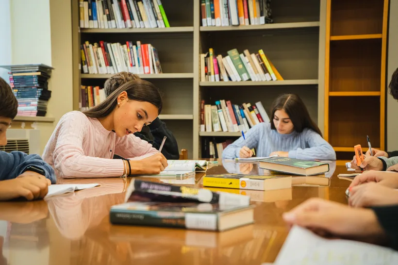Ragazzi che studiano insieme a un grande tavolo in biblioteca