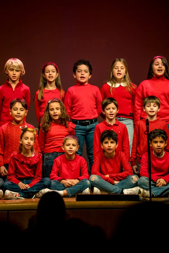 Il coro dei bambini vestiti di rosso sul palco dello spettacolo di Natale