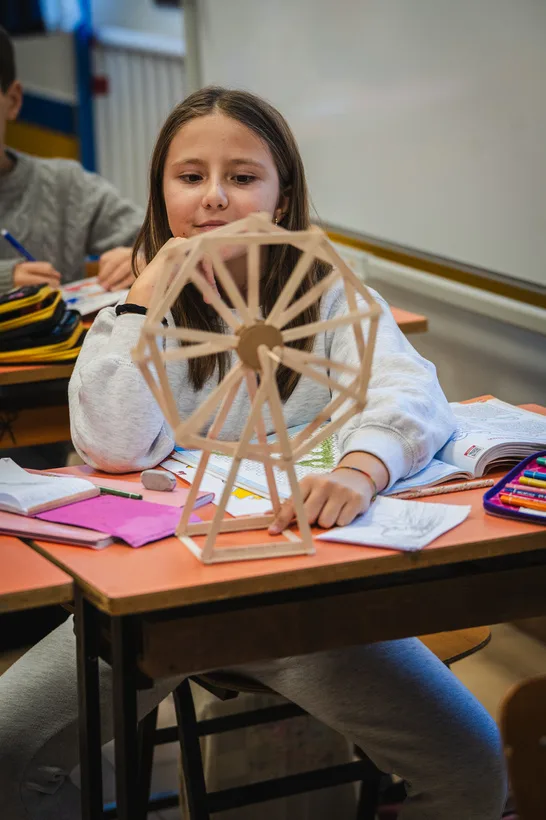 Una bambina costruisce un modellino di ruota panoramica in legno