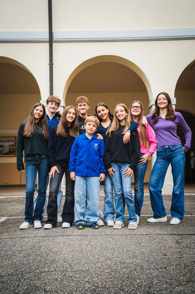 Un gruppo di ragazzi e bambini sorridenti nel porticato della scuola