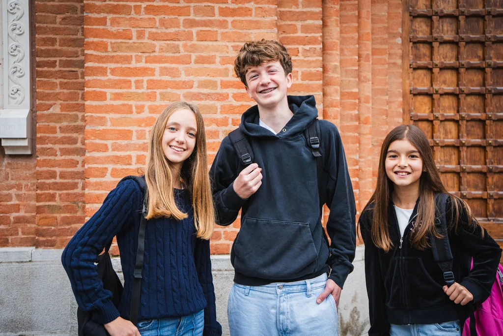 Tre ragazzi della secondaria davanti a un muro di mattoni